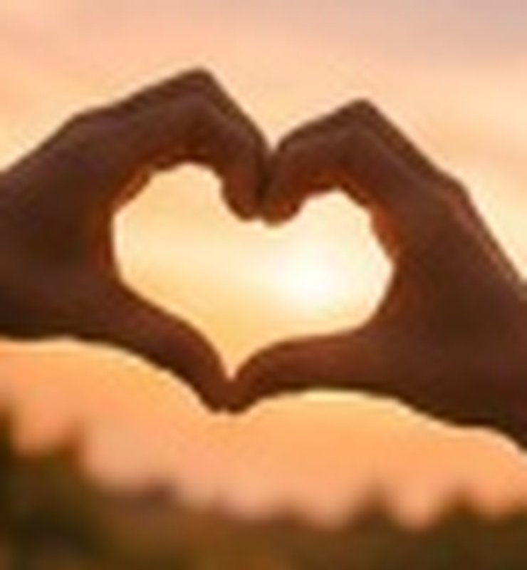 Hands forming a heart at sunset
